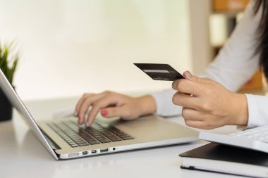 Kadın kredi kartı tutuyor ve iş adamlarında veya girişimcilerde çalışmak için dizüstü bilgisayar kullanıyor, online alışveriş, ecommerce, konsept internet bankacılığı, para harcamaları, vergiler