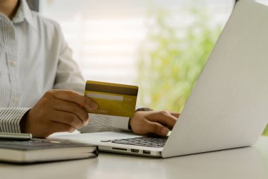 Kadın kredi kartı tutuyor ve iş adamlarında veya girişimcilerde çalışmak için dizüstü bilgisayar kullanıyor, online alışveriş, ecommerce, konsept internet bankacılığı, para harcamaları, vergiler