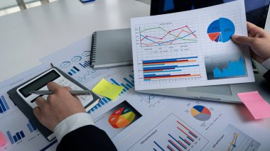 Elinde kalem olan bir bilgisayar ve hesap makinesi kullanan bir muhasebeci para kazanıyor ve masadaki evde yapılan harcamaları analiz ediyor..