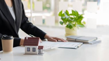 İş adamı ya da ev satış temsilcisi, iş yerinde sözleşmeli belgeler ve dizüstü bilgisayarlı hesap makinesiyle çalışan iş adamı ya da ev satış temsilcisi olarak çalışır. faiz, vergi ve karı hesaplamak için