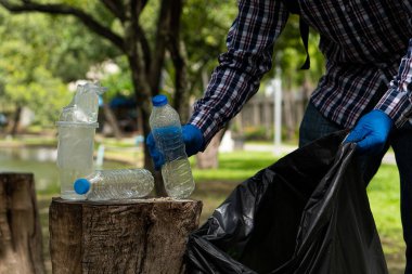 Gönüllüler parktaki gönüllü çöp toplama etkinliği sırasında parktaki geri dönüştürülmüş plastik şişeleri topluyorlar. Mutlu insanlar bölgeyi siyah torbalarla temizler. ekolojik kavram