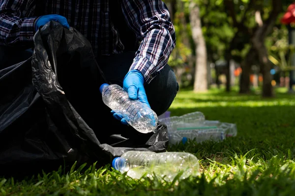 Gönüllüler parktaki gönüllü çöp toplama etkinliği sırasında parktaki geri dönüştürülmüş plastik şişeleri topluyorlar. Mutlu insanlar bölgeyi siyah torbalarla temizler. ekolojik kavram