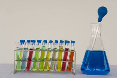 Tıbbi bilim laboratuarı kimyasal ilaç laboratuarı. Beher içinde hastane suyu ve mavi kimya laboratuvarı arka planında çeşitli renklerde cam şişeler.