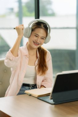 Heyecanlı bir Asyalı kız öğrenci işini bitirip iyi haberler aldıktan sonra tablet ekranına bakar..