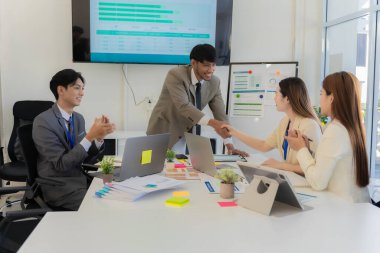 Şirket çalışanları ofiste çalışıyor. Asyalı pazarlama ekibi bilgisayar ekranında web sitesi tasarımını analiz ediyor.