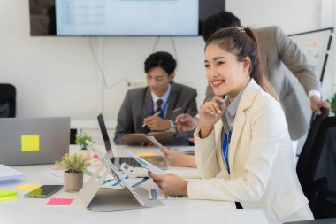 Şirket çalışanları ofiste çalışıyor. Asyalı pazarlama ekibi bilgisayar ekranında web sitesi tasarımını analiz ediyor.