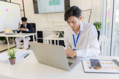 Şirket çalışanları ofiste çalışıyor. Asyalı pazarlama ekibi bilgisayar ekranında web sitesi tasarımını analiz ediyor.