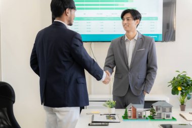 İki işadamı, masa, iş ve yatırım anlaşması, ortaklık tokalaşması, gayrimenkul anlaşması gibi ev modelleriyle el sıkışıyor..