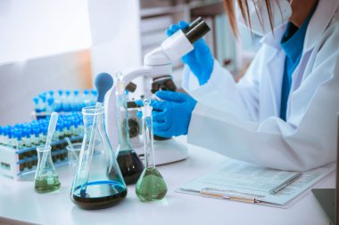 Bilim insanları modern laboratuvar tıbbi araştırmalarını kullanarak cam test tüplerindeki temiz sıvılarla deney yapıyorlar. Sağlık yeniliklerini geliştirme deneyleri.