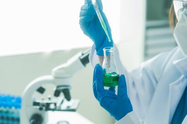 Bilim insanları modern laboratuvar tıbbi araştırmalarını kullanarak cam test tüplerindeki temiz sıvılarla deney yapıyorlar. Sağlık yeniliklerini geliştirme deneyleri.