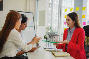 Ev satın alma sözleşmesinin imzalanmasını açıklamak yerine, banka müdürü gayrimenkul yatırım belgelerini tartışıyor ve açıklıyor..