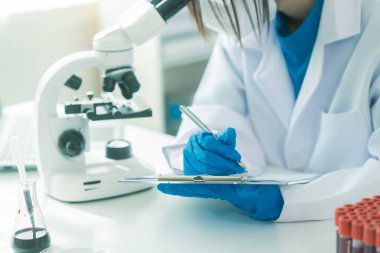 Bilim insanları modern laboratuvar tıbbi araştırmalarını kullanarak cam test tüplerindeki temiz sıvılarla deney yapıyorlar. Sağlık yeniliklerini geliştirme deneyleri.