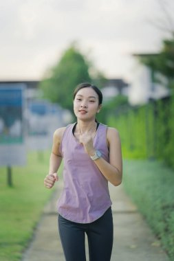 Güzel Asyalı kadın egzersiz koşusu için kollarını uzatıyor. Kadın, koşmadan ya da parkta egzersiz yapmadan önce ısınmak için kollarını uzatıyor..