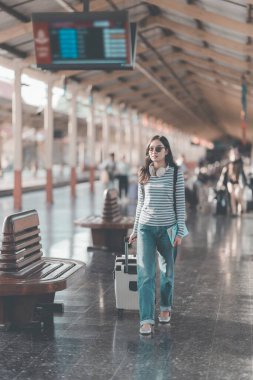 Sırt çantalı Asyalı kadın tren istasyonunda bavulunu tutarken, trenin hareket etmesini beklerken, yolculuk için heyecanlıydı..