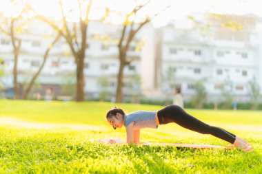 Güzel Asyalı kadın egzersiz koşusu için kollarını uzatıyor. Kadın, koşmadan ya da parkta egzersiz yapmadan önce ısınmak için kollarını uzatıyor..