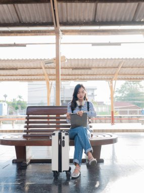 Sırt çantalı Asyalı kadın tren istasyonunda bavulunu tutarken, trenin hareket etmesini beklerken, yolculuk için heyecanlıydı..