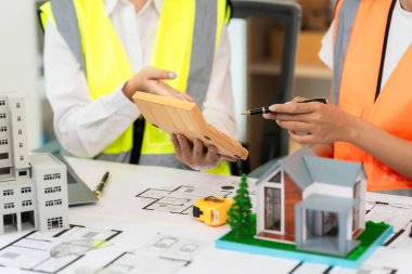 İnşaat mühendisleri ve mimarlar inşaat planlarını, proje ilerlemesini ve konut projesine yönelik tasarım planlarını tartıştılar.