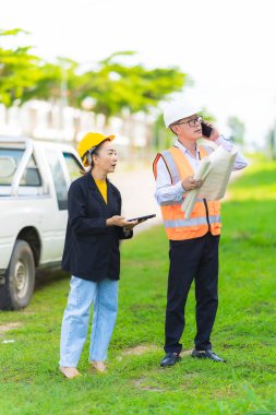 Asyalı erkek ve kadın mühendislerden oluşan bir ekip bina planlarına, inşaat mühendisliğine, iç teftişe ve konut geliştirme çalışmalarına göre bir binanın yapısını inceliyor..