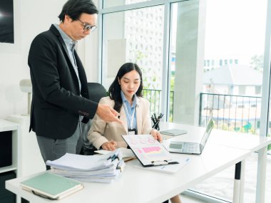 Asya 'nın kıdemli iş adamı ve genç sekreteri mali belgeler ve dizüstü bilgisayarla çalışıyor..