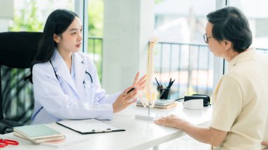 Asyalı kadın doktor son sınıf erkek hastasıyla konuşuyor. Vücut ağrısı hakkında tavsiye veriyor. Tıbbi personel tıbbi geçmişi kaydediyor..