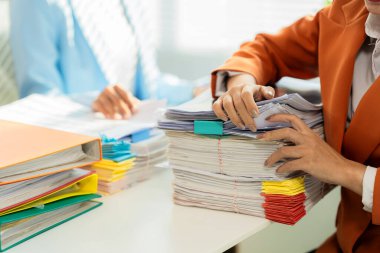 Masada iki genç ofis çalışanı belgeler ve dizüstü bilgisayarla çalışıyor. Ortaklar belgeleri gözden geçirir, şirket toplantısında mali raporları okur.