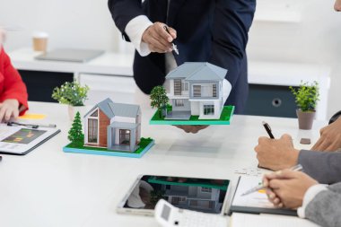 Bir emlakçı, yeni ev satın alan bir çifte sigorta poliçesini açıklayarak toplantıda kilit şartları ve gelecekteki yatırımları vurguladı..