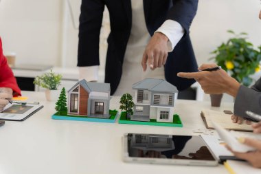 Bir emlakçı, yeni ev satın alan bir çifte sigorta poliçesini açıklayarak toplantıda kilit şartları ve gelecekteki yatırımları vurguladı..