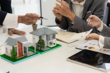 Bir emlakçı, yeni ev satın alan bir çifte sigorta poliçesini açıklayarak toplantıda kilit şartları ve gelecekteki yatırımları vurguladı..