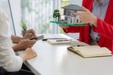 Bir emlakçı, yeni ev satın alan bir çifte sigorta poliçesini açıklayarak toplantıda kilit şartları ve gelecekteki yatırımları vurguladı..