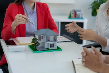 Bir emlakçı, yeni ev satın alan bir çifte sigorta poliçesini açıklayarak toplantıda kilit şartları ve gelecekteki yatırımları vurguladı..