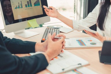 Two accountants use calculators to perform company financial calculations, handle accounting on laptop computers at their desks, manage budgets, and handle financial tasks.