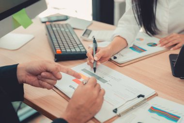 İki muhasebeci şirketin mali hesaplamalarını yapmak için hesap makinelerini kullanır, bilgisayarlarında muhasebe ile ilgilenir, bütçeleri yönetir ve finansal işlerle ilgilenir..