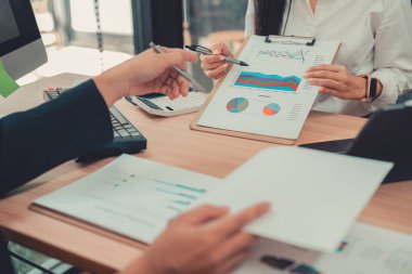 İki muhasebeci şirketin mali hesaplamalarını yapmak için hesap makinelerini kullanır, bilgisayarlarında muhasebe ile ilgilenir, bütçeleri yönetir ve finansal işlerle ilgilenir..