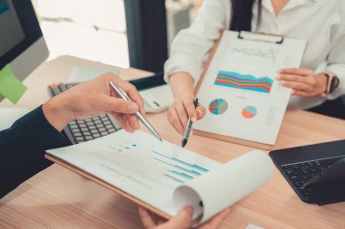 İki muhasebeci şirketin mali hesaplamalarını yapmak için hesap makinelerini kullanır, bilgisayarlarında muhasebe ile ilgilenir, bütçeleri yönetir ve finansal işlerle ilgilenir..