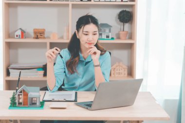 Genç bir emlakçı kız müşterilerine internet üzerinden danışmanlık hizmeti sunuyor..