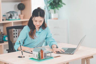 Genç bir emlakçı kız müşterilerine internet üzerinden danışmanlık hizmeti sunuyor..