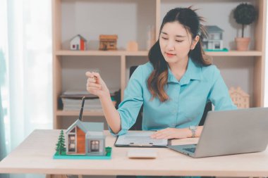 Genç bir emlakçı kız müşterilerine internet üzerinden danışmanlık hizmeti sunuyor..