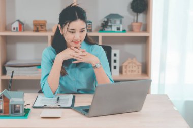 Genç bir emlakçı kız müşterilerine internet üzerinden danışmanlık hizmeti sunuyor..