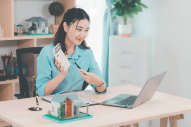 Genç bir emlakçı kız müşterilerine internet üzerinden danışmanlık hizmeti sunuyor..