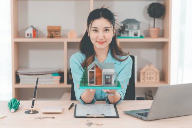 Genç bir emlakçı kız müşterilerine internet üzerinden danışmanlık hizmeti sunuyor..