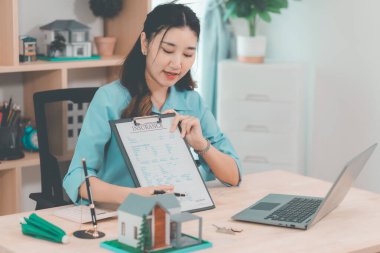 Genç bir emlakçı kız müşterilerine internet üzerinden danışmanlık hizmeti sunuyor..