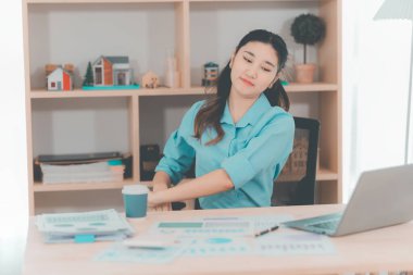 Asyalı bir kadın muhasebeci masasında çalışırken şiddetli bir ağrı yaşadı. Bu da kötü bir duruş ya da uzun süre oturma durumu olduğunu gösteriyor..