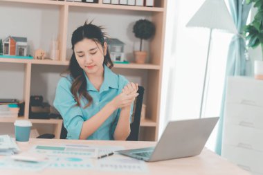 Asyalı bir kadın muhasebeci masasında çalışırken şiddetli bir ağrı yaşadı. Bu da kötü bir duruş ya da uzun süre oturma durumu olduğunu gösteriyor..