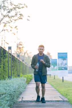 Genç bir Asyalı sabah bir parkta dışarıda koşuyor. Sağlık için egzersiz kavramı tasvir edilmiştir..