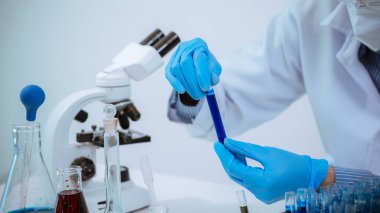 Bilim: Teknisyen laboratuvar önlüğü ve eldiven giyerken, bir doktorun eli laboratuarda analiz için bir tüp alıyor..