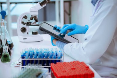 Bilim: Teknisyen laboratuvar önlüğü ve eldiven giyerken, bir doktorun eli laboratuarda analiz için bir tüp alıyor..