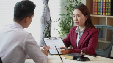 Hukuk ve adalet kavramı: Avukat genç kadın avukatlara hukuki danışmanlık yapar, yasal belgeleri tartışır ve önemli davalarda rehberlik eder.