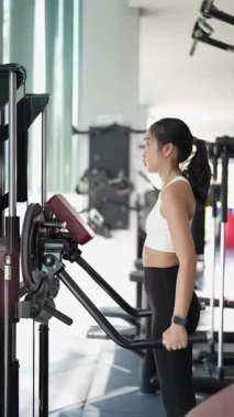 Kararlı ve güçlü bir Asyalı kadın spor salonundaki spor salonunda ağırlık kaldırıyor. Vücut çalışıyor, kas yapmak için ağırlık çalışıyor ve kaldırıyor sağlıklı bir yaşam tarzı konsepti..