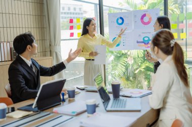 Asyalılar arasında başarılı takım çalışmalarının sonuçlarını gösteren çizelge ve grafikleri tartışmak üzere bir iş grubu toplantısı yapılıyor..