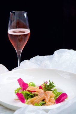 Roket salatasında somon ve bir bardak köpüklü şarap.